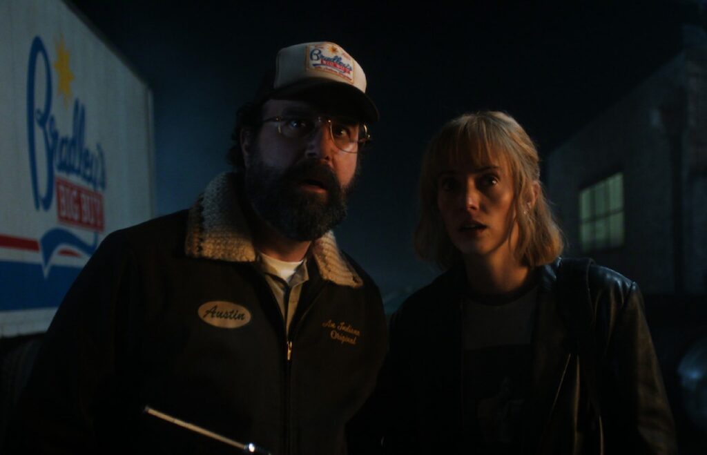 beared man in baseball cap and young woman looking ahead in alarm