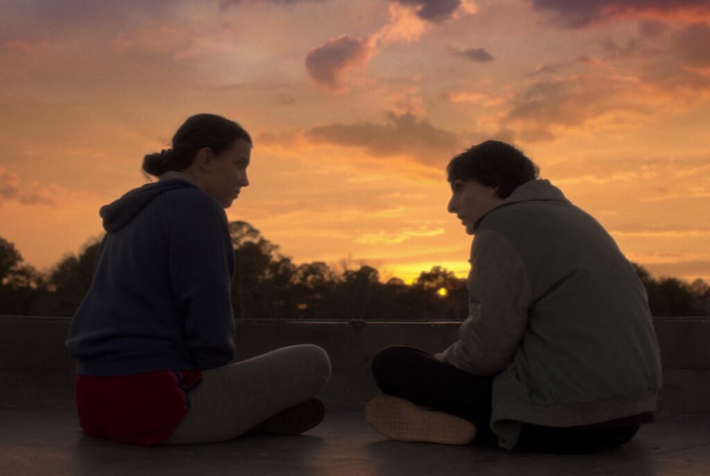 young woman and man on a rooftop at sunset