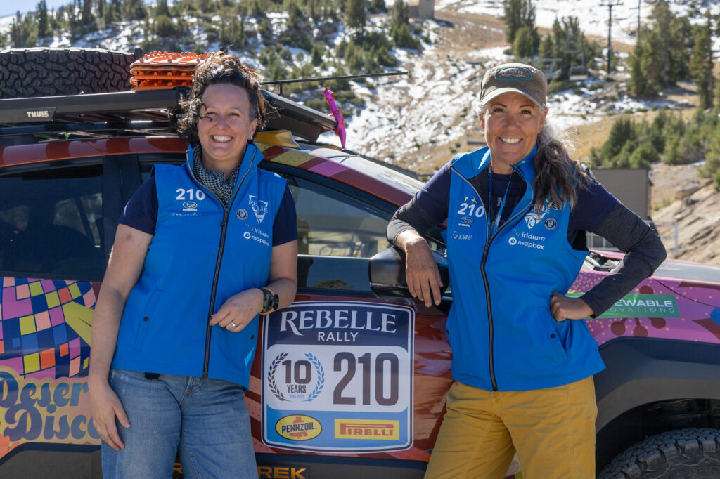 Two women rally drivers stand in front of their car