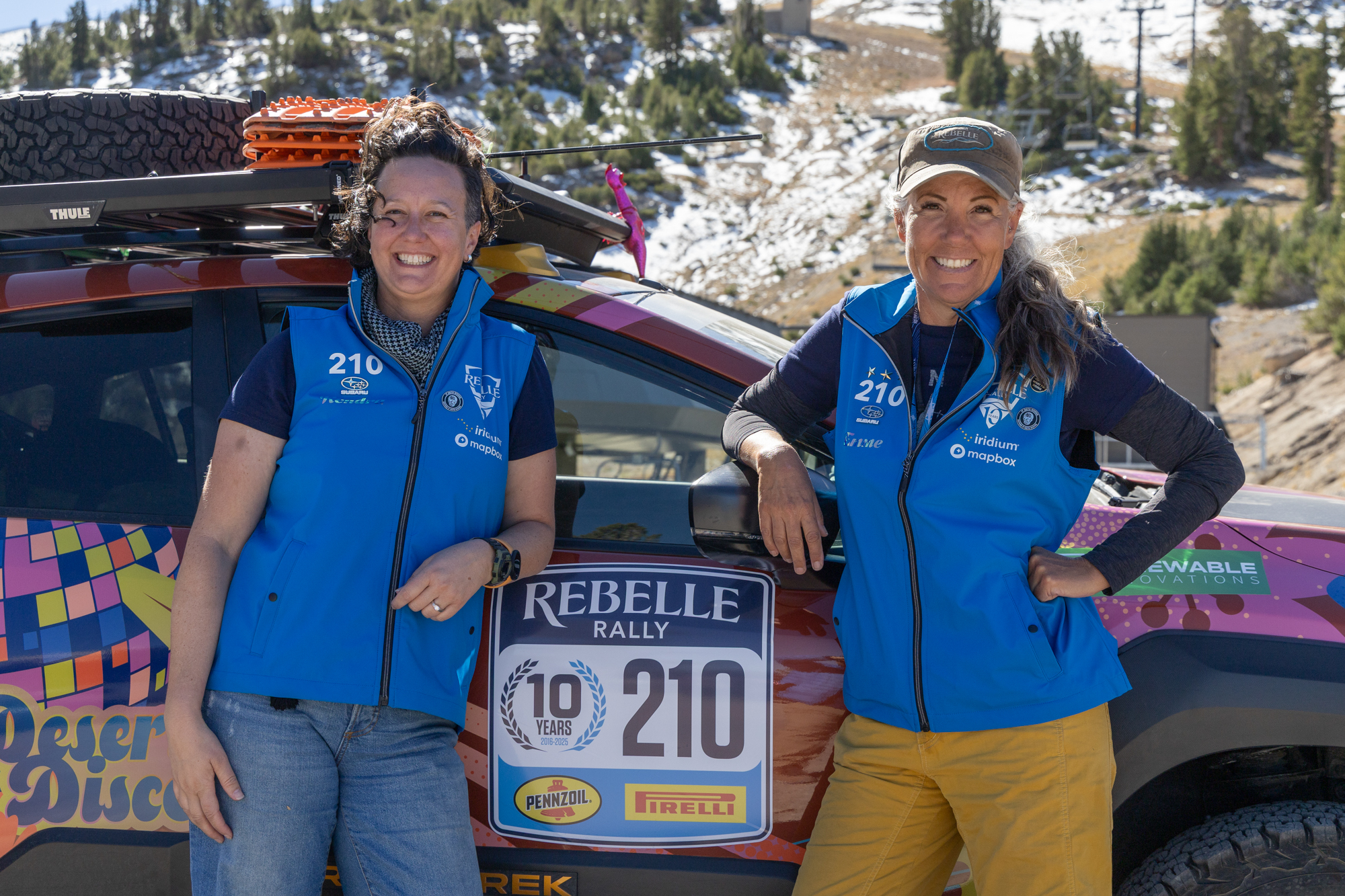 Two female rally drivers standing in front of their car