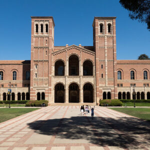 Image of a red brick building at the end of a pathway on a grassy campus.