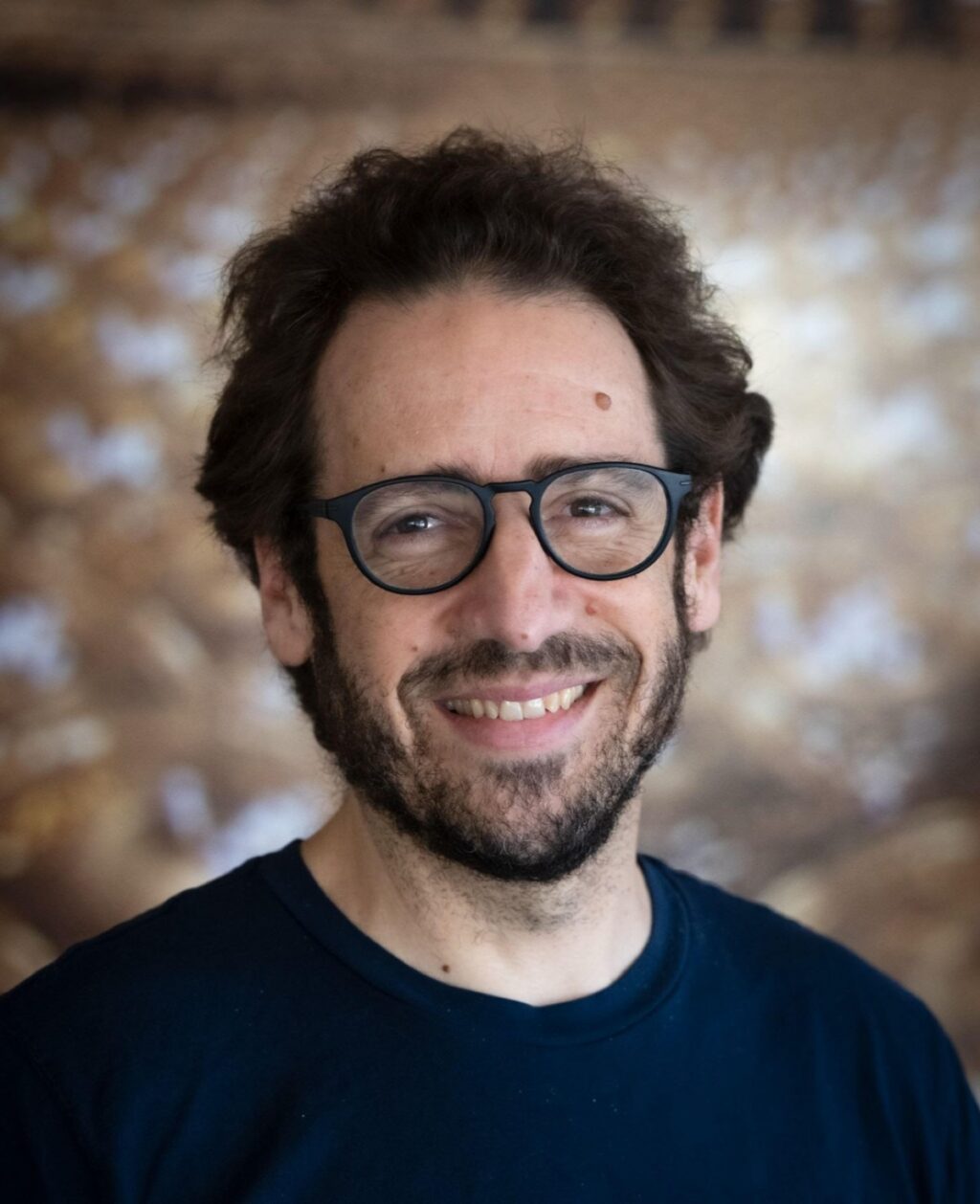 author photo of a bearded dark haired man in glasses and black t-shirt