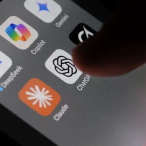 A person's finger tapping a ChatGPT app icon on an iPhone screen that also shows icons for DeepSeek, Gemini, Copilot, Grok, and Claude.