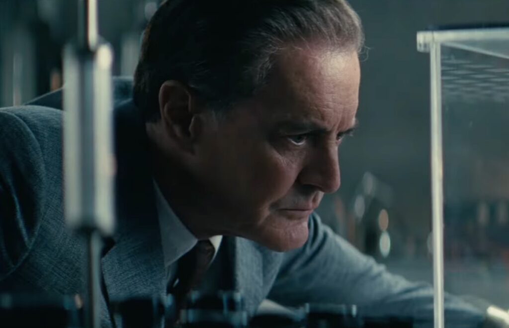 Uomo anziano in camicia che guarda attentamente dentro un contenitore di vetro in un laboratorio