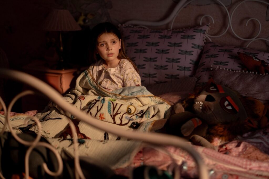 young girl in bed at night looking scared