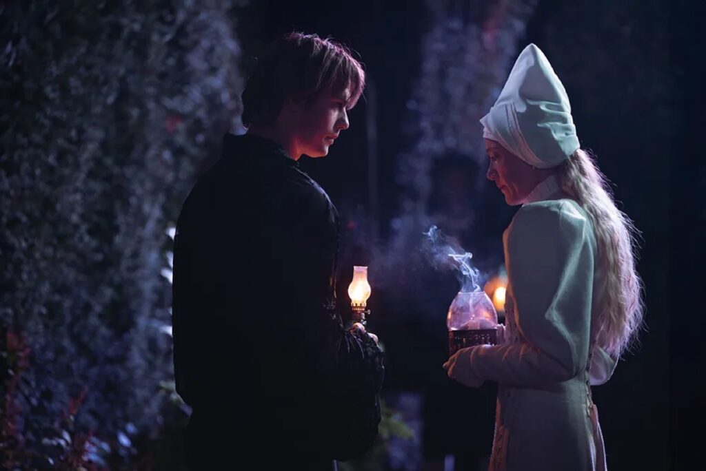 man and woman in medieval dress holding lamps at night