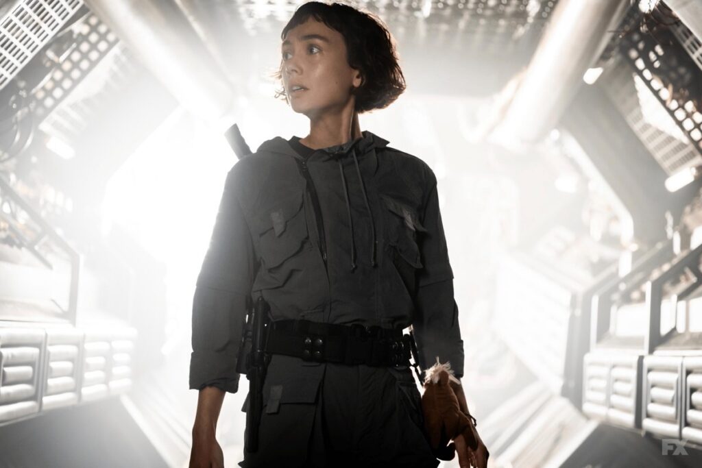 young woman standing in a futuristic corridor bathed in white light