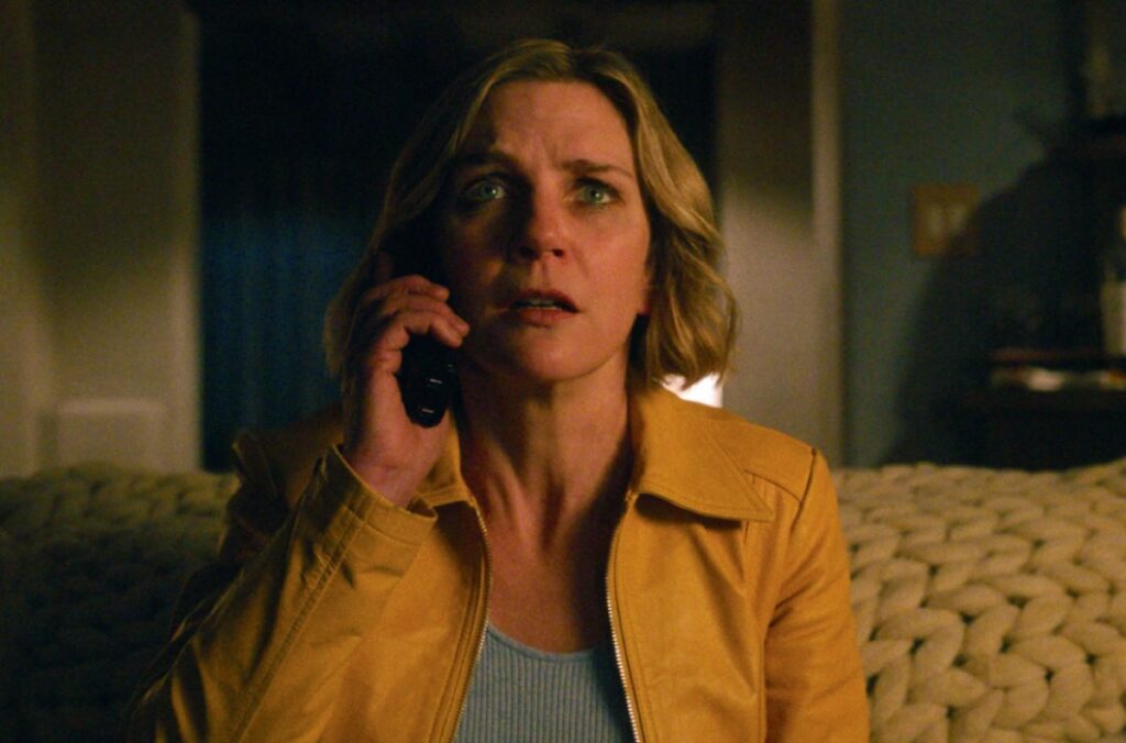 blond woman on cell phone in yellow jacket looking dismayed
