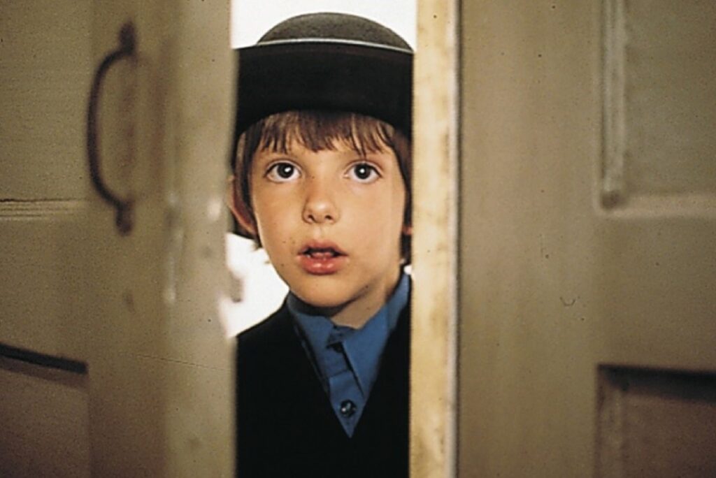 little Amish boy peeking through a crack in the door