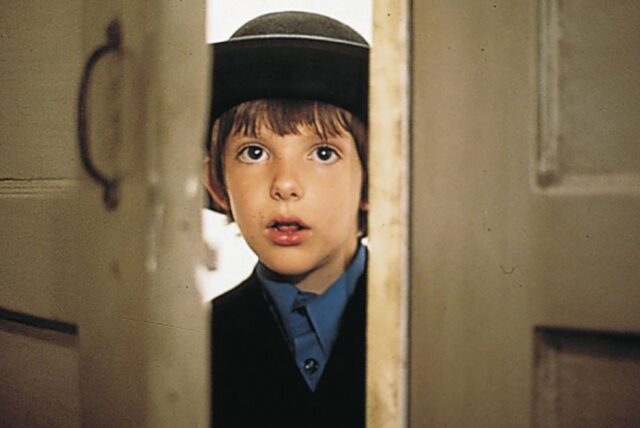 little Amish boy peeking through a crack in the door