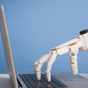 Image of a robotic hand pressing a laptop's keyboard.