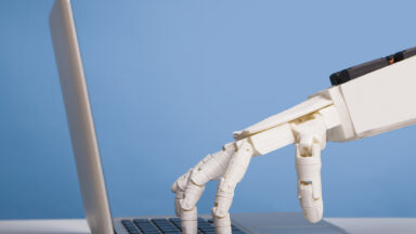 Image of a robotic hand pressing a laptop's keyboard.