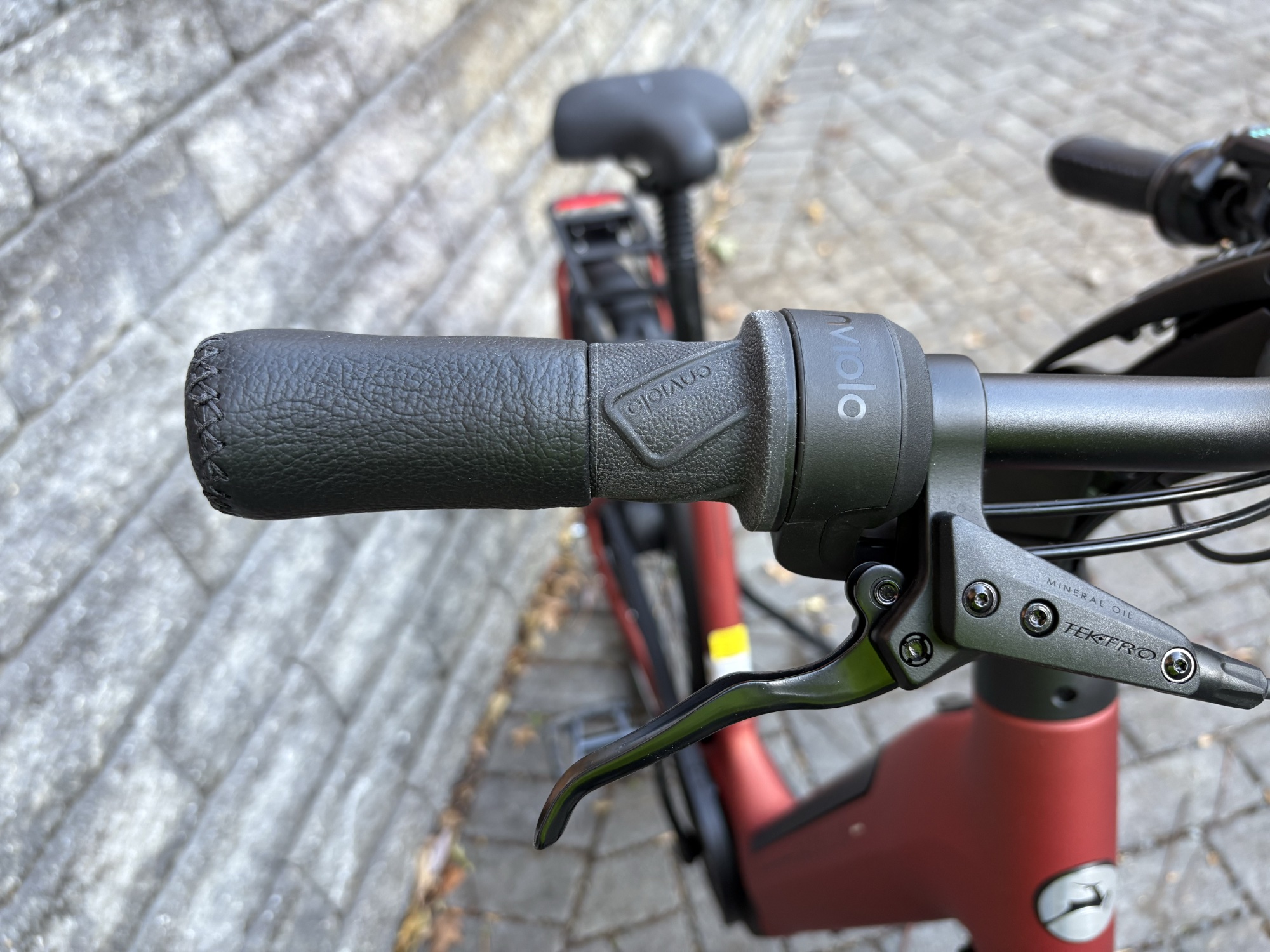 Image of a portion of the handlebar of an electric bike, with the bike itself behind it.