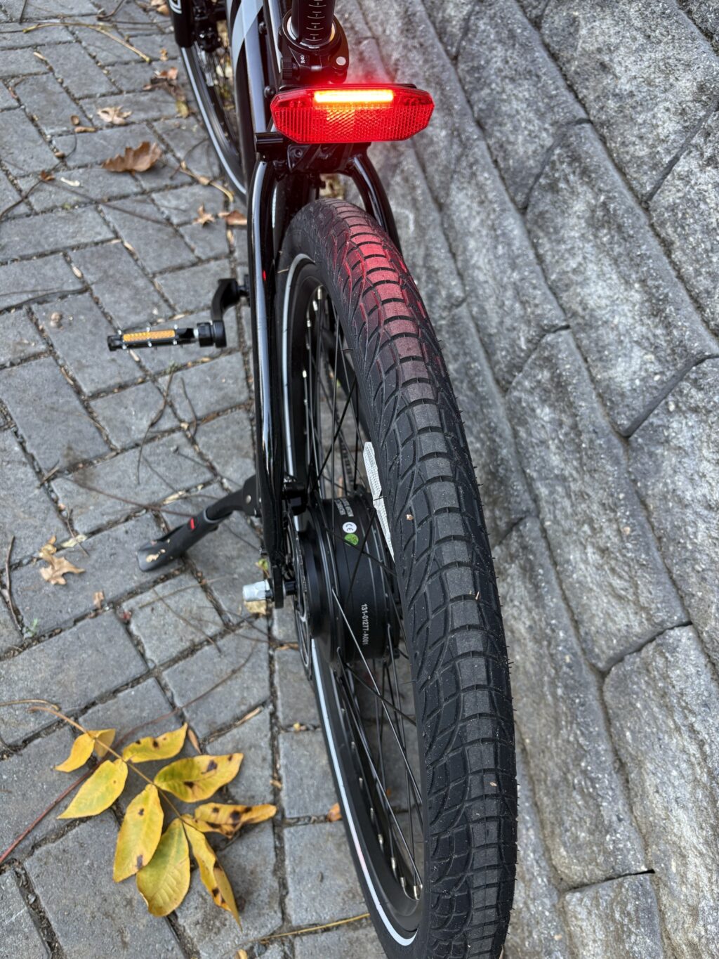 Image of the rear wheel of a bicycle, with a red light between it and the seat.