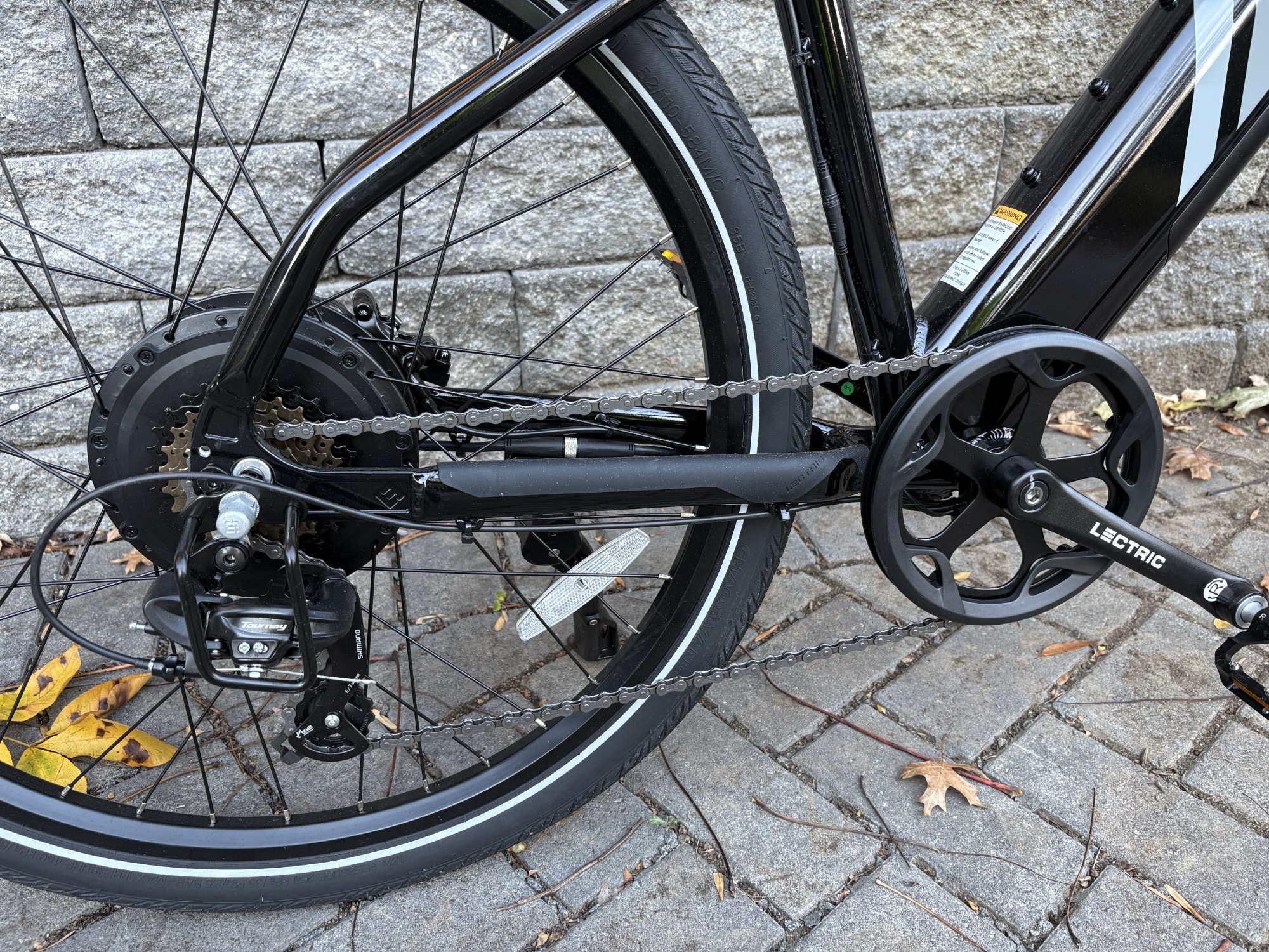 Image of the cranks and rear wheel of a black metal bicycle.