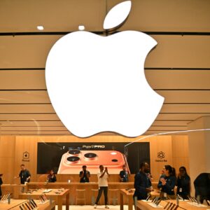 A large Apple logo hangs over employees at an Apple Store in India.