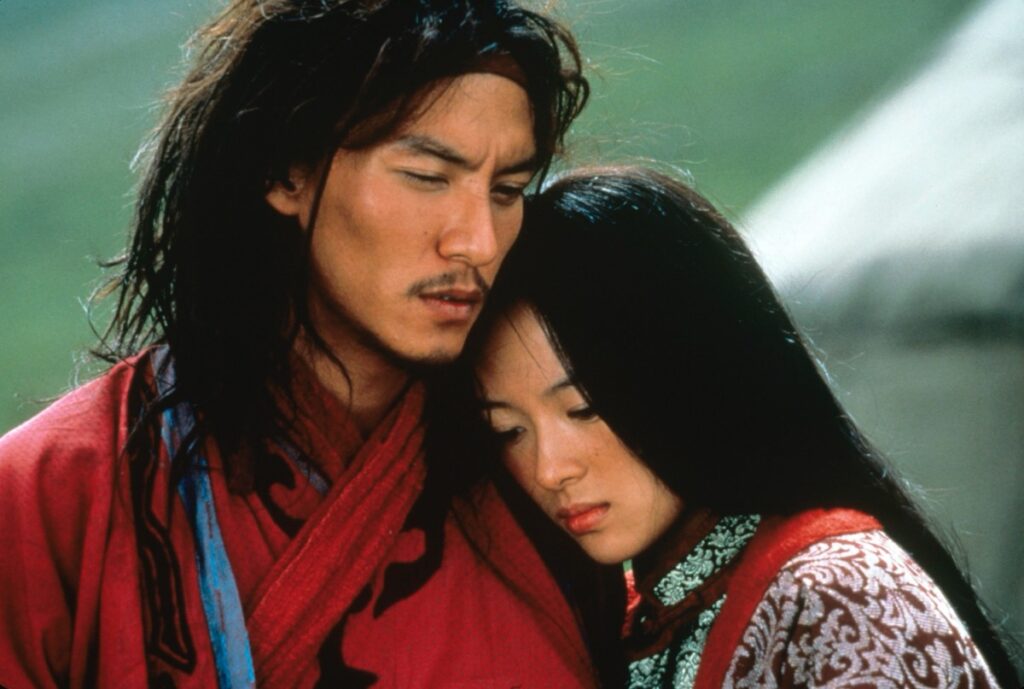 Asian man with long hair embracing young Asian woman, both in traditional Qing dynasty garb