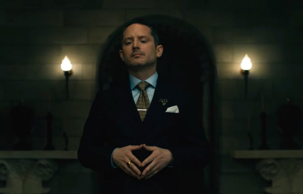 clean cut man in suit standing with fingers touching in front of him.