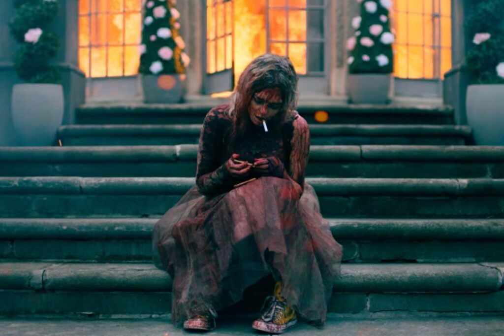 blood soaked bedraggled bride lighting cigarette on mansion steps as the house burns behind her