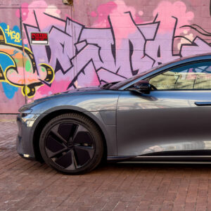 A Lucid Air parked in front of a graffiti mural