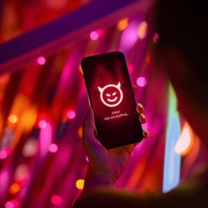 Female hand holding smartphone showing an evil with devil horn on her AI chatbot conversation app in the city. Illustrating the ideas around the risks and dangers of Artificial Intelligence (AI).