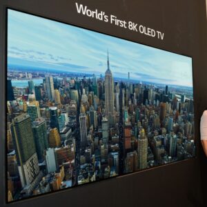 A man and woman standing next to a TV labeled the "world's first 8K OLED TV."