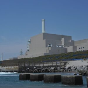 Image of a large, blocky concrete building located up a small slope from the ocean.