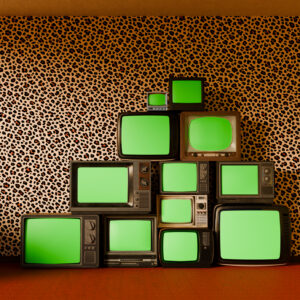 pyramid stack of vintage televisions, each with a vibrant green screen, set against bold leopard-patterned wallpaper and a luxurious red carpet floor.