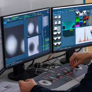 Image of a person sitting in front of a set of computer monitors showing the output of complicated imaging hardware.