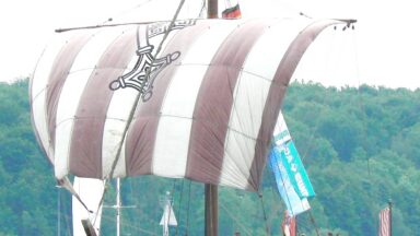 photo of a sailing ship with a single mast and a square sail painted red and white