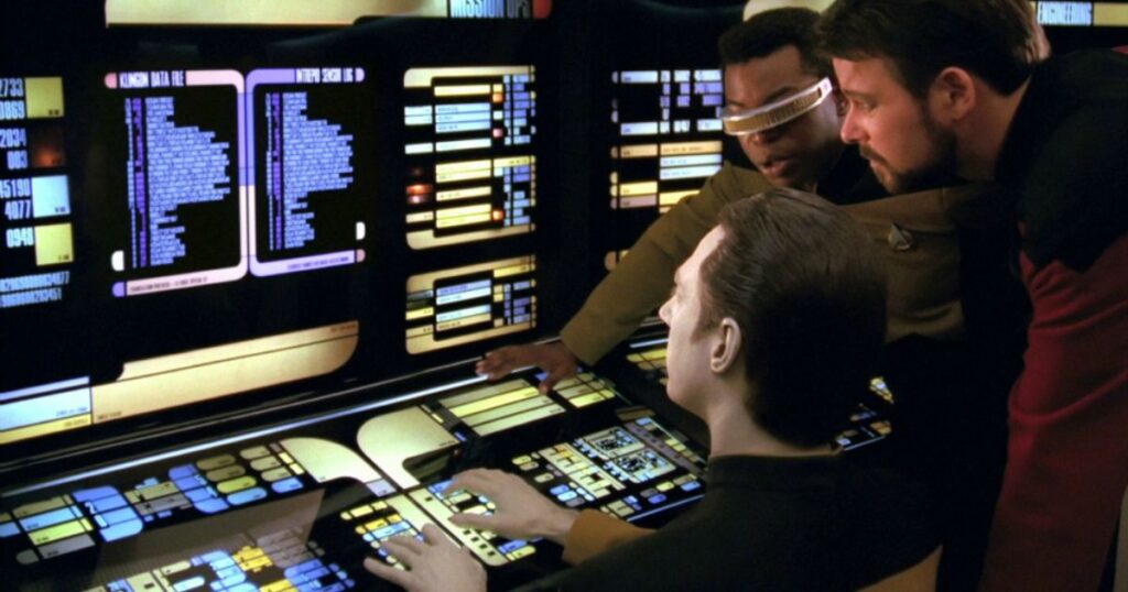 Screenshot of Data, Geordi, and Riker collaboratively coding at one of the bridge's aft science stations