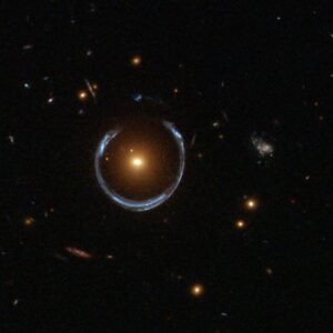 Image of a field of stars with a single bright object in the middle. The object is surrounded by a wispy, distorted ring.