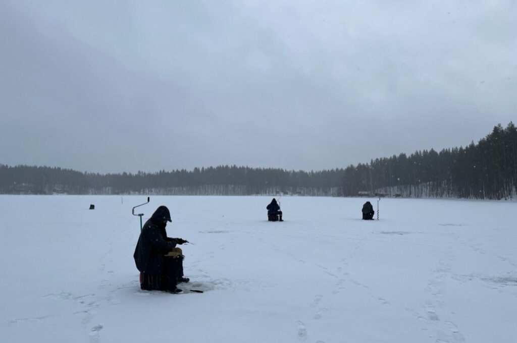 ice fishers sitting on the ice