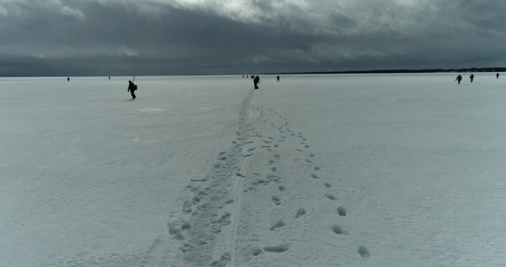 Finnish icefishers distributed on a lake with footsteps in the foreground.