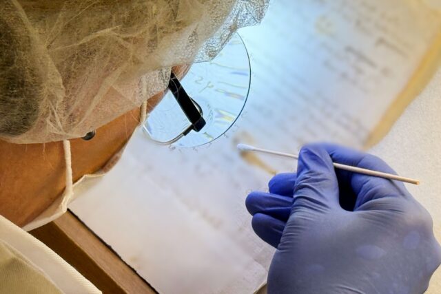 Artist Karina Åberg swabs a 14th century da Vinci family letter from the State Archive in Prato for biological clues, following research initiated by Rossella Lorenzi.