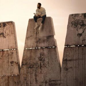 man sitting on top of a giant stone W