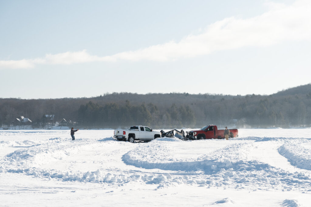 plough trucks shape ice on a frozen lake.