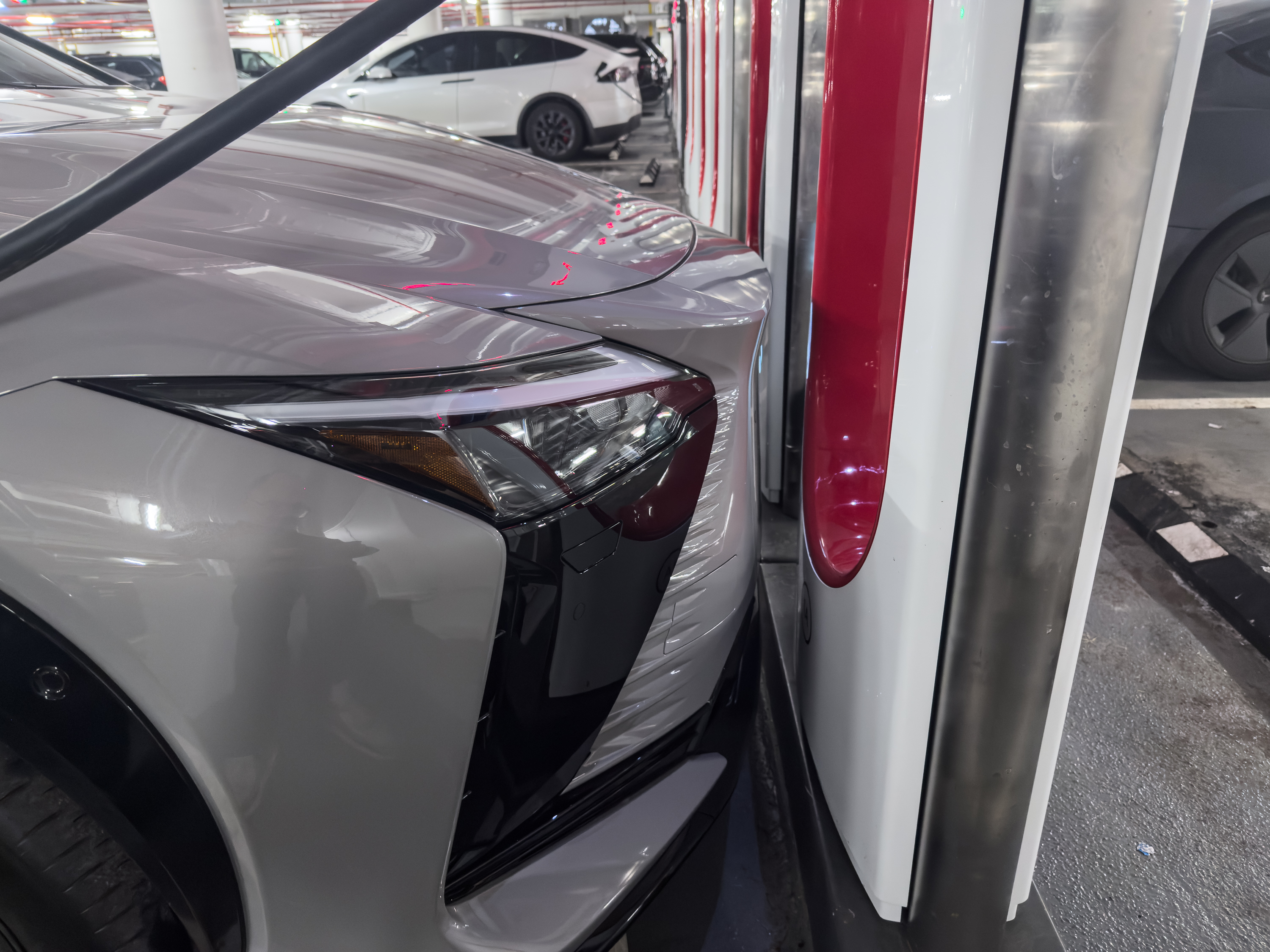 A Lexus EV parked very close to a Tesla Supercharger