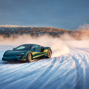 A blue McLaren Artura drifting on a frozen lake