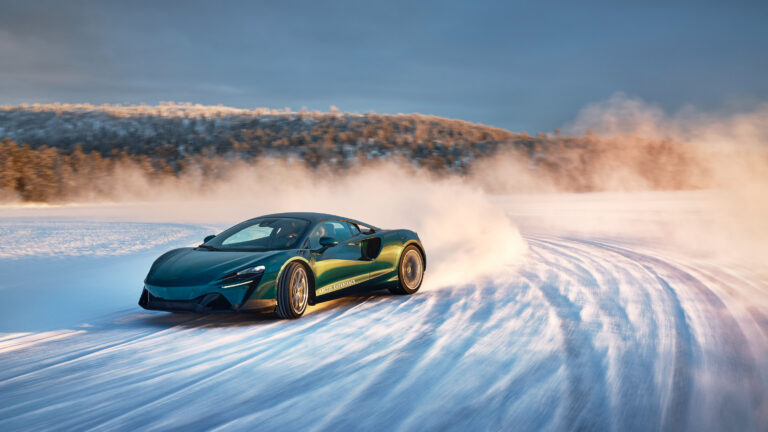 A blue McLaren Artura drifting on a frozen lake