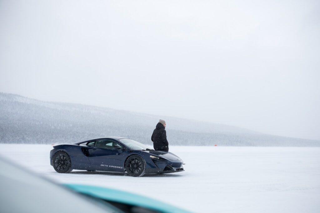 A person stands next to a McLaren Artura on a frozen lake