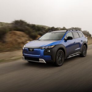 A blue Subaru trailseeker drives past the camera