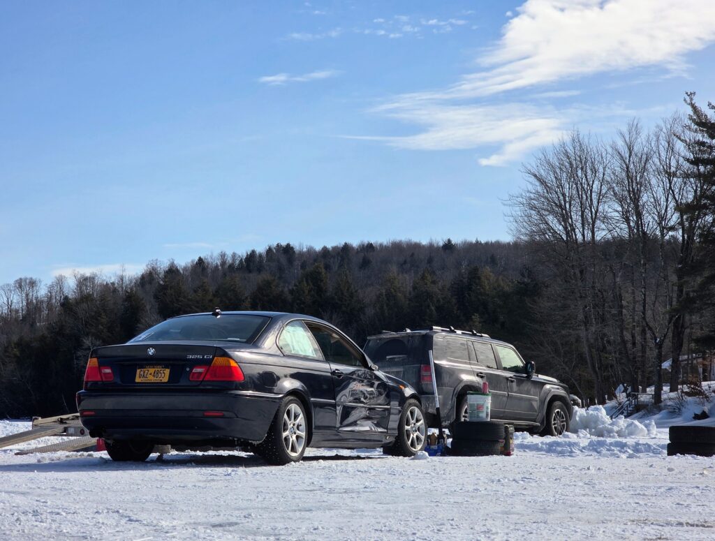 A black BMW 3 Series with a damaged door on the passenger side.