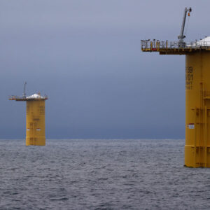 Image of a series of metal cylinders rising vertically from the ocean.