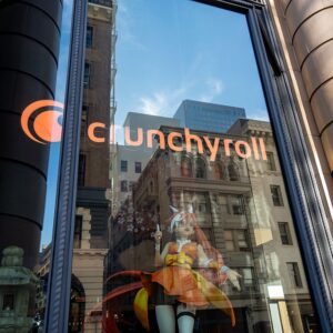 Logo for Crunchyroll on window with anime figure visible inside window.