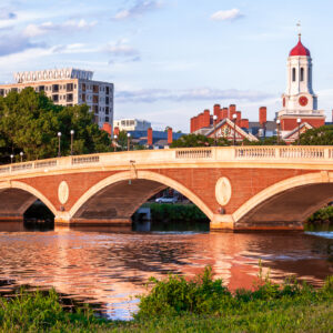 A red brick arched bridge, with a white tower behind it.
