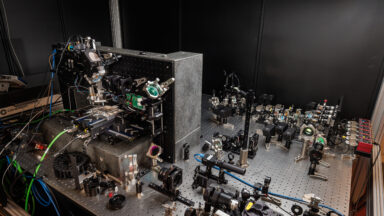 A table top covered with lenses and optical equipment, with a microscope on one side.