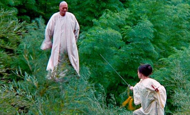 Asian man in long white garb confronting young Asian woman brandishing a sword in the bamboo treetops
