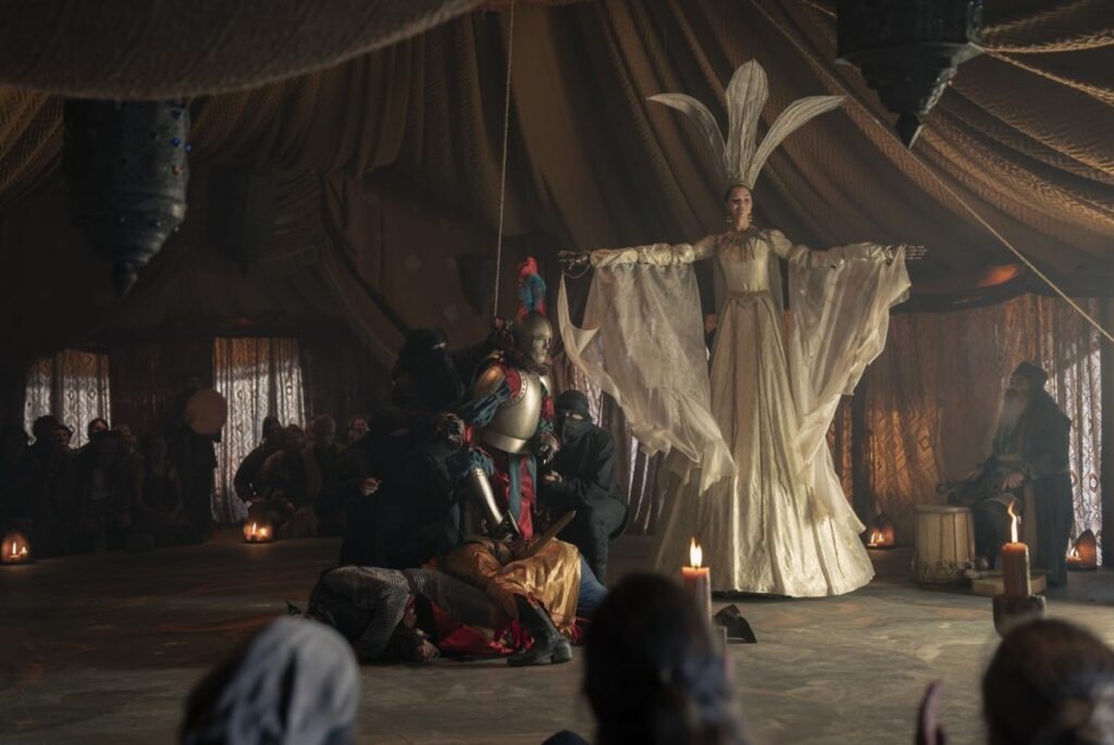 people on a makeshift stage in a tent, acting out a story with large puppets