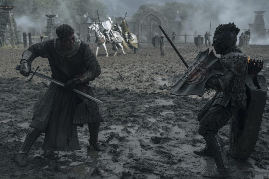 Two muddy, bloodied knights face each other wielding swords